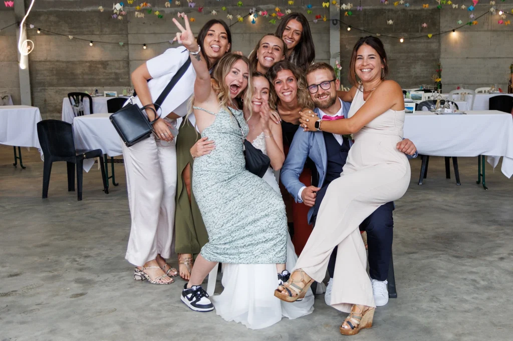 Groupe d'invités défilant rapidement devant les mariés pour une photo rush de mariage, sourires et énergie.