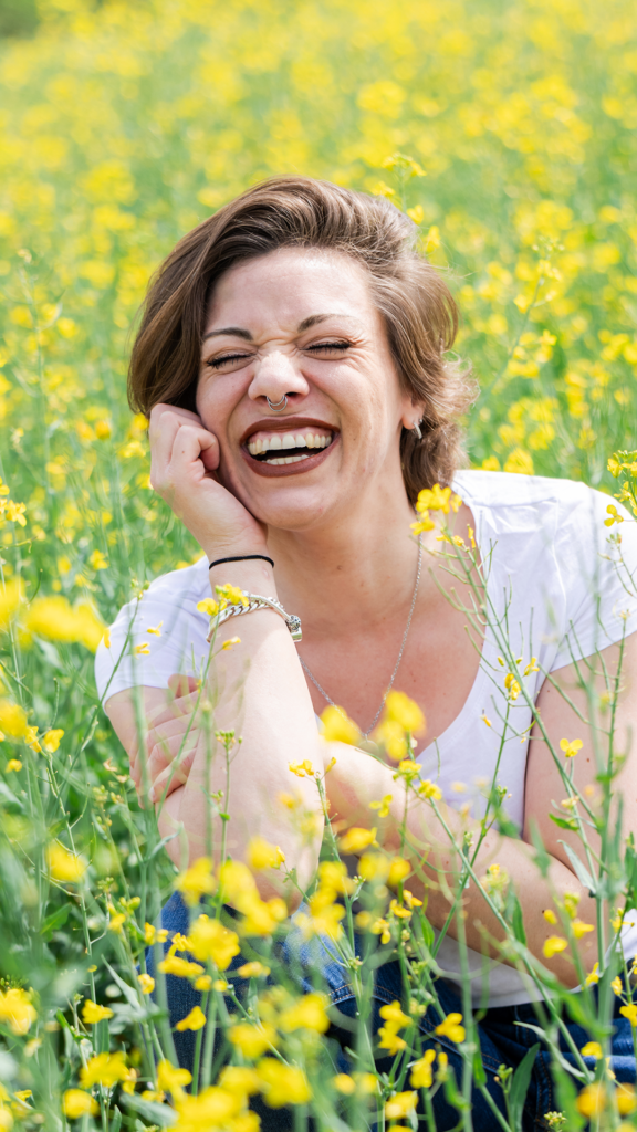 Femme en t-shirt blanc dans les colzas jaunes au printemps, Isère