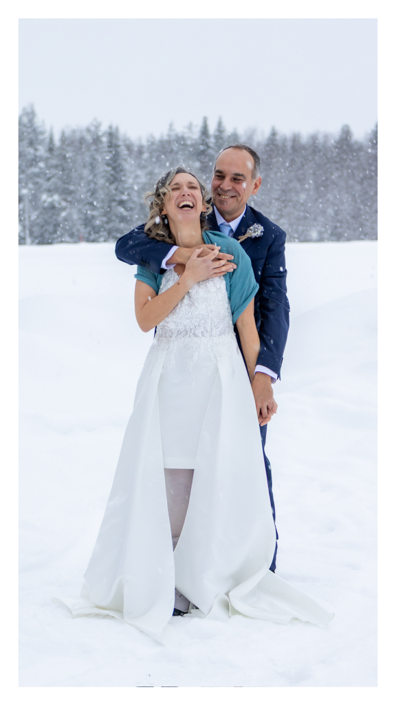 hotographe de mariage Sandra Vial plan large couple mariés elopement paysage Laponie hiver neige et sapins enneigés.