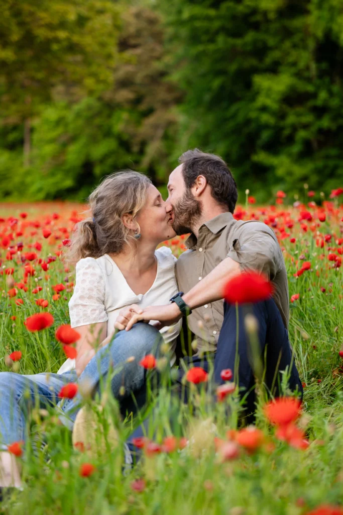 Couple assis dans les coquelicots, fleurs en premier plan flou, Isère printemps