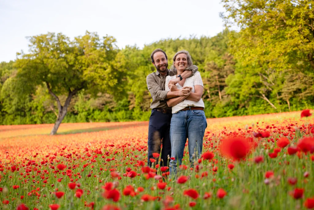 Couple complice et souriant dans les coquelicots en Isère, style documentaire