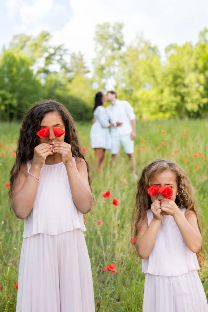 Deux sœurs qui cachent leurs yeux avec des coquelicots rouges, Isère