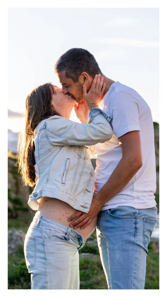 Couple qui s'embrasse à contre-jour au coucher de soleil, séance grossesse Alpe d'Huez Isère