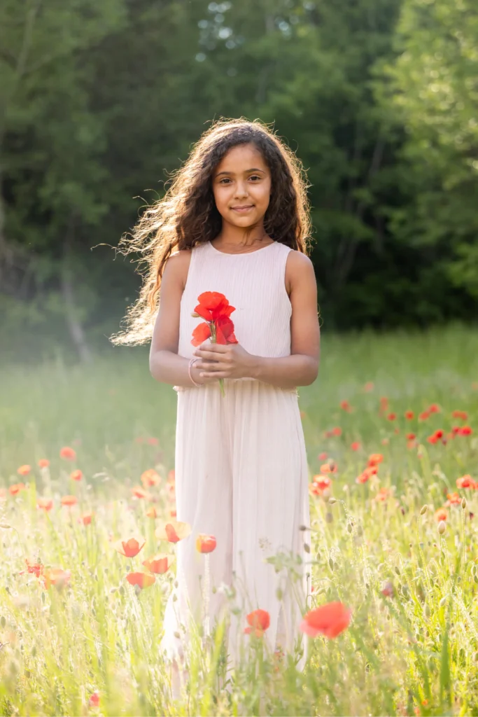 Portrait de fillette souriante dans les coquelicots en lumière naturelle, Isère