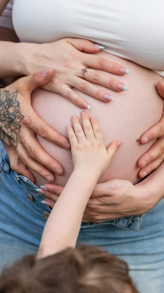 Gros plan photo du ventre d'une femme enceinte avec les mains de toute la famille posées dessus