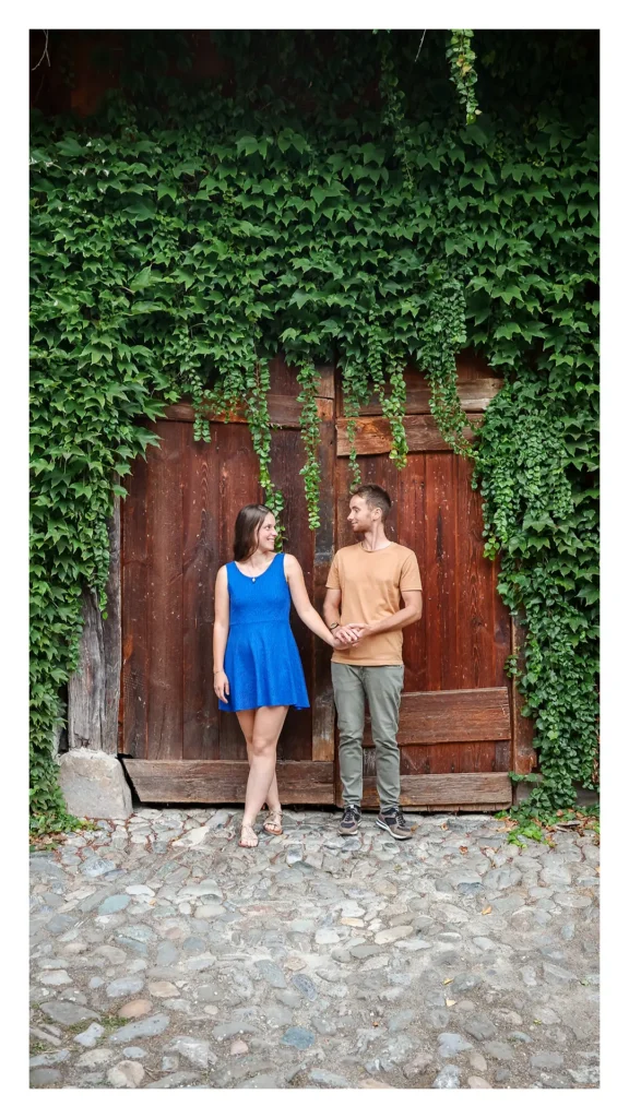 Couple posant devant une porte en bois couverte de lierre à Yvoire